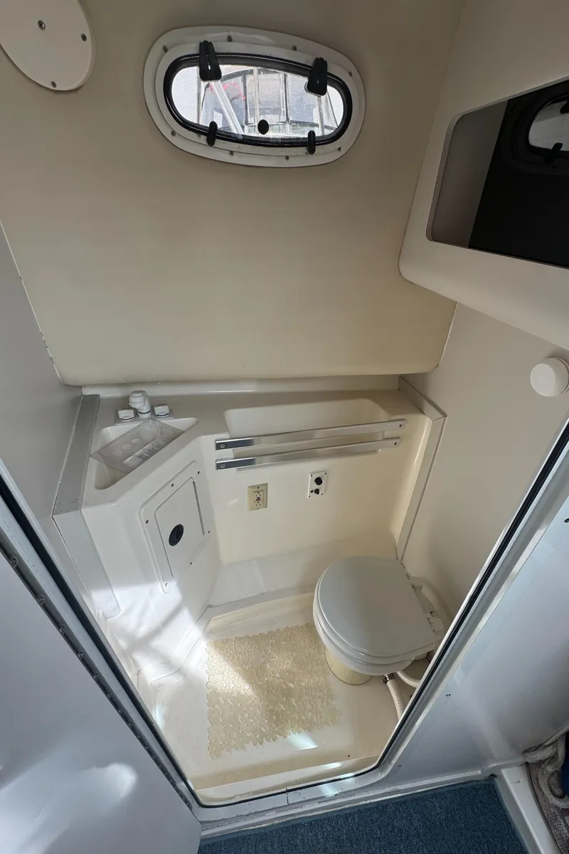 Slide: The Image of 2001 Mako 293 Walkaround boat bathroom with compact toilet and sink. - 19