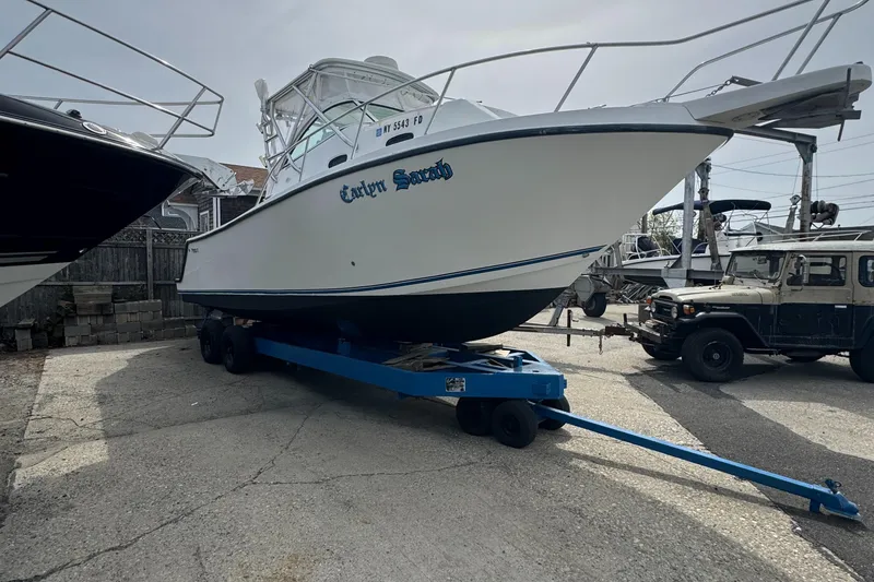 Slide: The Image of 2001 Mako 293 Walkaround boat on trailer in a marina setting. - 2