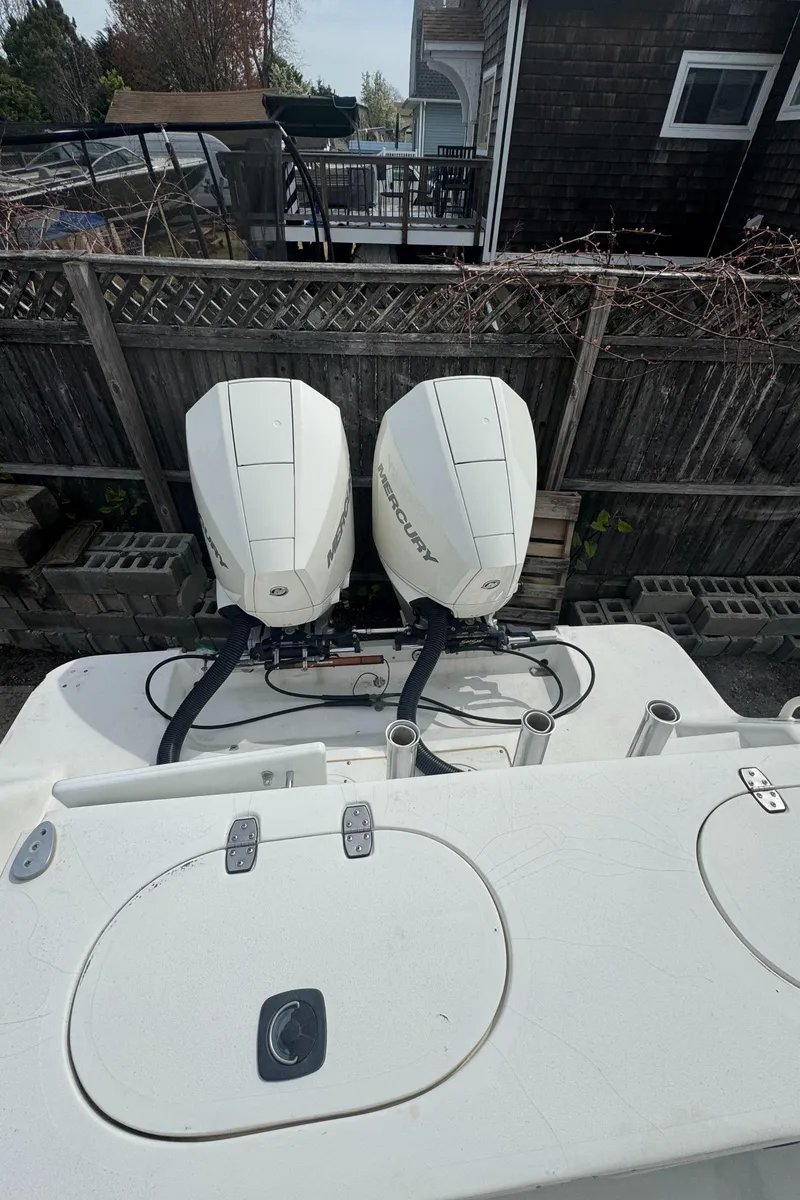 Slide: The Image of 2001 Mako 293 Walkaround boat with dual outboard engines, docked near a wooden fence. - 7