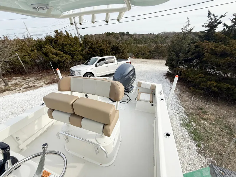Slide: The Image of 2019 Parker 23 Special Edition boat with beige seating, parked near a white truck and trees. - 15