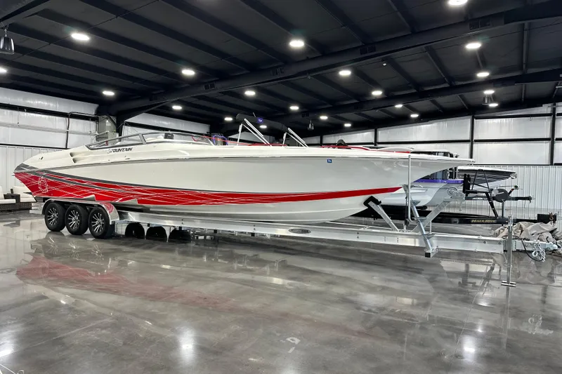Slide: The Image of 2008 Fountain 38 Lightning boat with red accents on a trailer in a spacious indoor facility. - 2