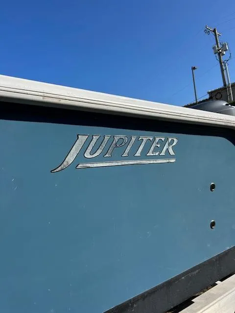 The Image of 2007 Jupiter 29FS boat side view with logo under clear blue sky. - 1