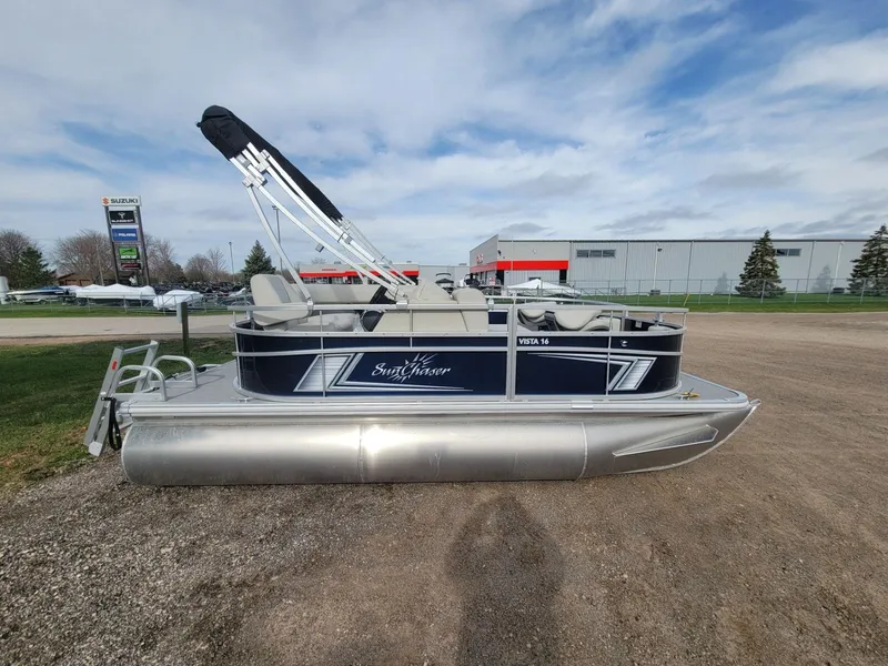 Slide: The Image of 2023 SunChaser Vista 16 Fish pontoon boat parked outdoors under a cloudy sky. - 1