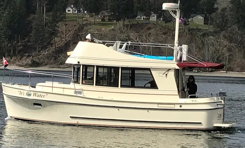 Slide: The Image of 2001 Camano Trawler boat cruising on a calm lake with forested shoreline. - 0