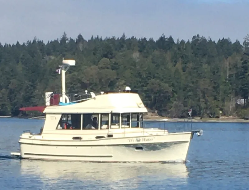 Slide: The Image of 2001 Camano Trawler cruising on a serene lake with forested shoreline in the background. - 1