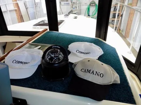 Slide: The Image of 2001 Camano Trawler interior with compass and branded hats on display. - 26