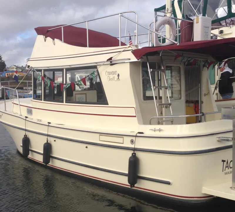 Slide: The Image of 2001 Camano Trawler boat docked, featuring maroon canopy and festive flags. - 3