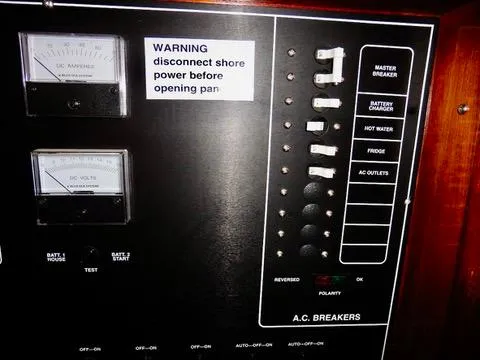 Slide: The Image of Electrical panel of a 2001 Camano Trawler with AC breakers and warning label. - 32