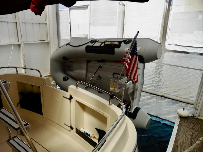Slide: The Image of 2001 Camano Trawler with inflatable dinghy and American flag in covered dock. - 42