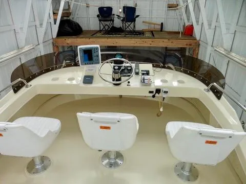 Slide: The Image of 2001 Camano Trawler helm with three white seats and navigation equipment in a covered dock. - 5