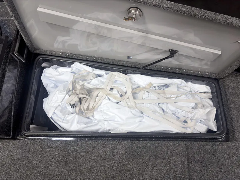 Slide: The Image of Storage compartment in a 2025 Caymas DV 22 boat, containing white fabric and straps. - 9