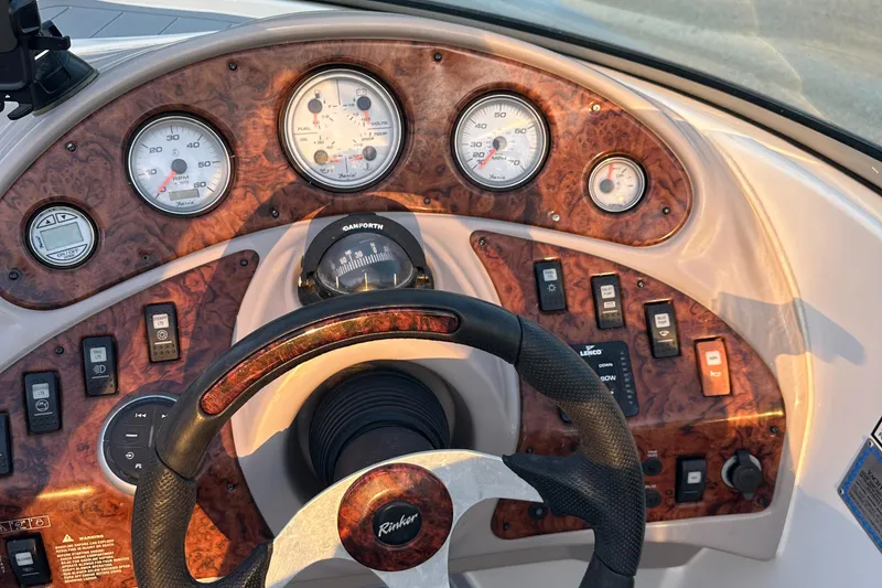 Slide: The Image of 2006 Rinker 262 Captiva Bowrider dashboard with gauges and controls, featuring a woodgrain finish. - 21