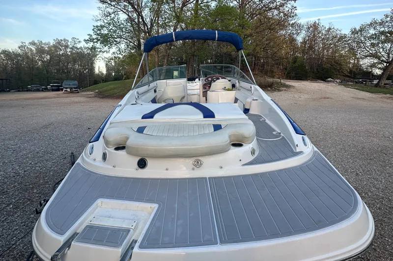 Slide: The Image of 2006 Rinker 262 Captiva Bowrider boat with blue canopy, parked on gravel. - 6
