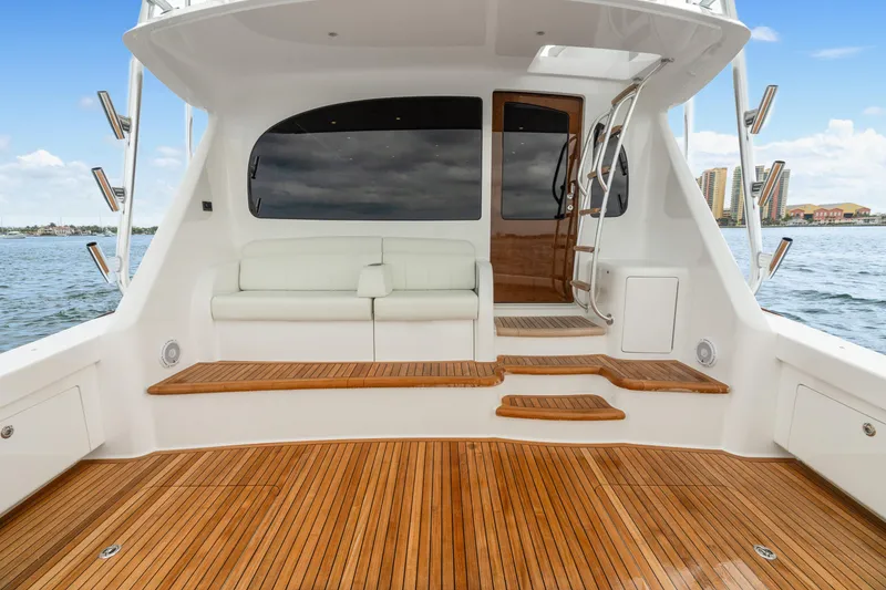 Slide: The Image of 2025 Viking 58 Convertible yacht with teak deck and white seating, docked by the water. - 31
