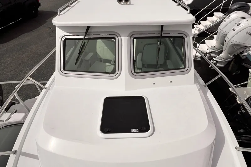 Slide: The Image of 2025 Parker 2420 boat, white exterior, dual windows, docked with visible outboard motors. - 12