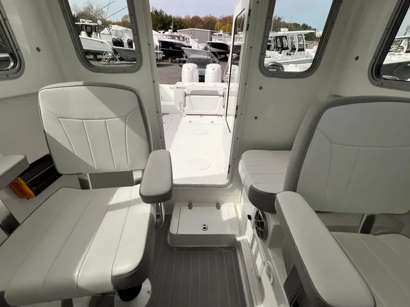 Slide: The Image of Interior of a 2025 Parker 2420 boat, featuring two cushioned seats and a view of the deck. - 2