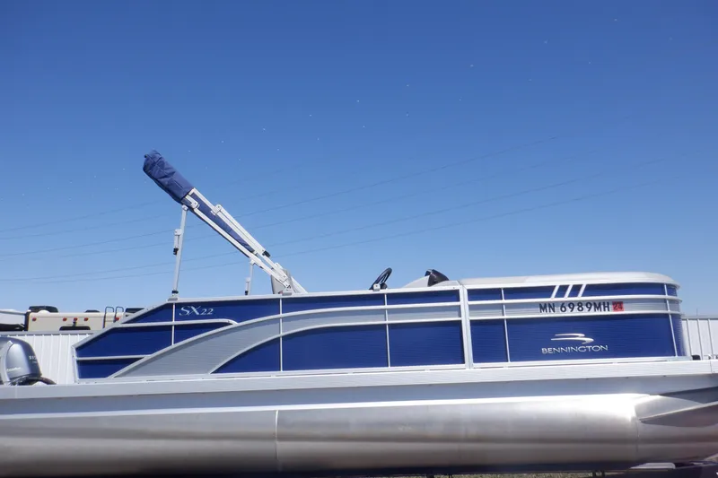 Slide: The Image of 2022 Bennington SX 22 Swingback pontoon boat under clear blue sky. - 1