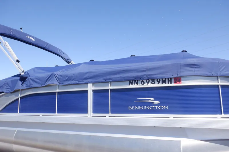 Slide: The Image of 2022 Bennington SX 22 Swingback pontoon boat with blue cover and visible registration number. - 47