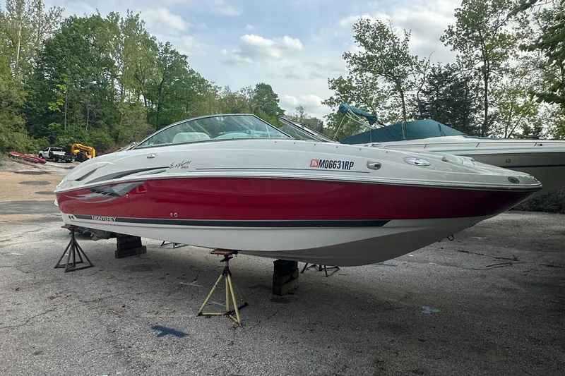 Slide: The Image of 2004 Monterey 253 Explorer Sport boat on stands, red and white hull, outdoor setting. - 1