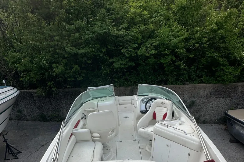 Slide: The Image of 2004 Monterey 253 Explorer Sport boat with white interior, parked near lush greenery. - 6