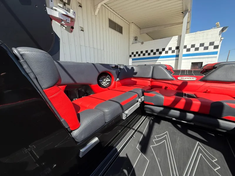 Slide: The Image of 2021 Supra SL boat interior with red and black seating, docked at a marina. - 11