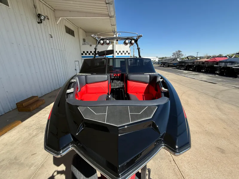 Slide: The Image of 2021 Supra SL boat with sleek black design and red interior, docked outdoors. - 3