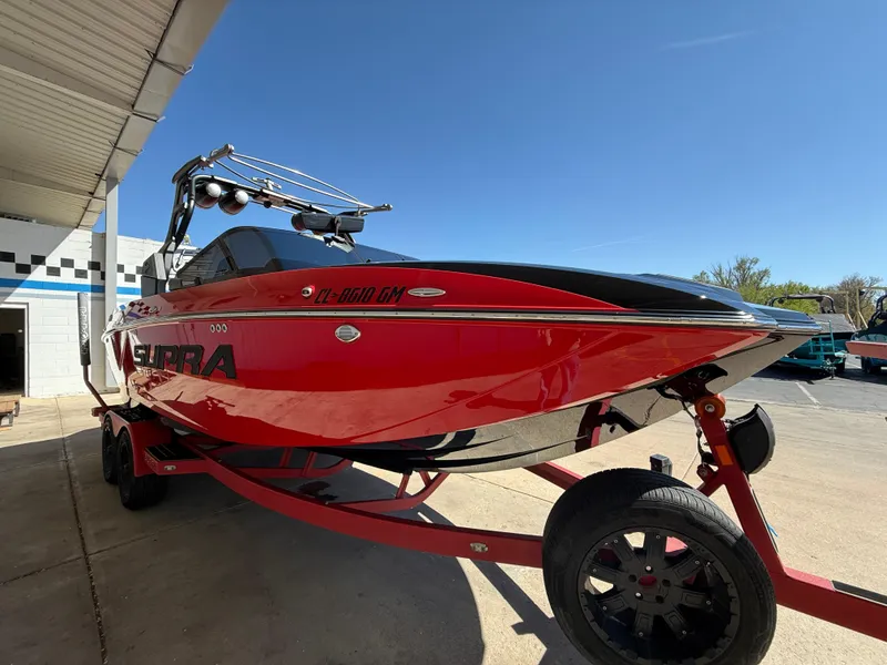 Slide: The Image of 2021 Supra SL boat in vibrant red on a trailer, parked outdoors. - 4