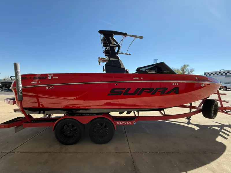 Slide: The Image of Red 2021 Supra SL boat on trailer, side view, under clear blue sky. - 5