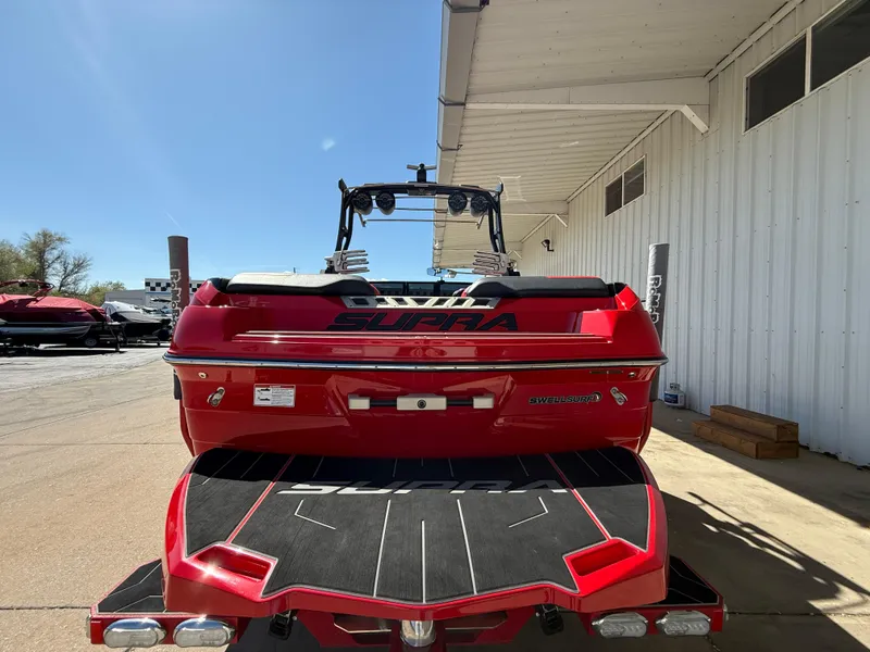 Slide: The Image of 2021 Supra SL boat, red, parked outside a white building under clear blue sky. - 8