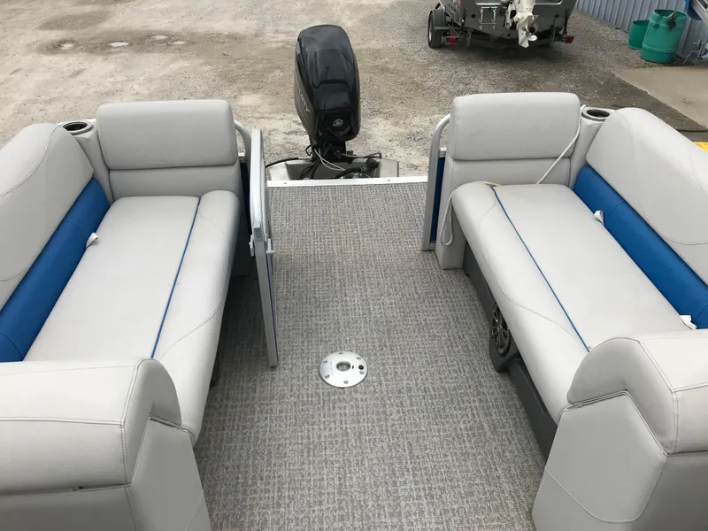 Slide: The Image of 2019 Avalon Venture Quad Lounge boat interior with gray and blue seating, outboard motor. - 14