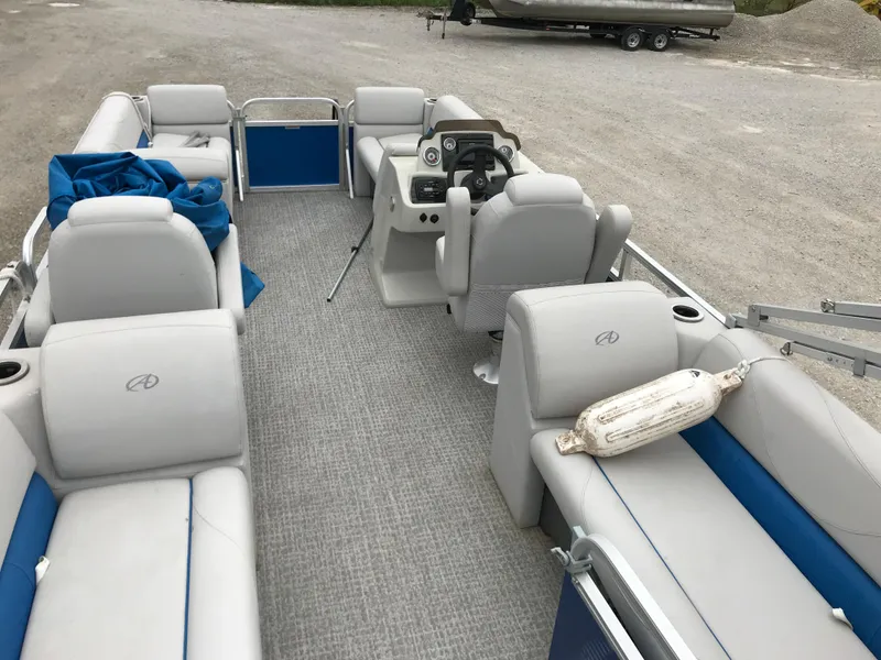 Slide: The Image of 2019 Avalon Venture Quad Lounge pontoon boat with gray and blue seating, steering console, and open deck. - 7