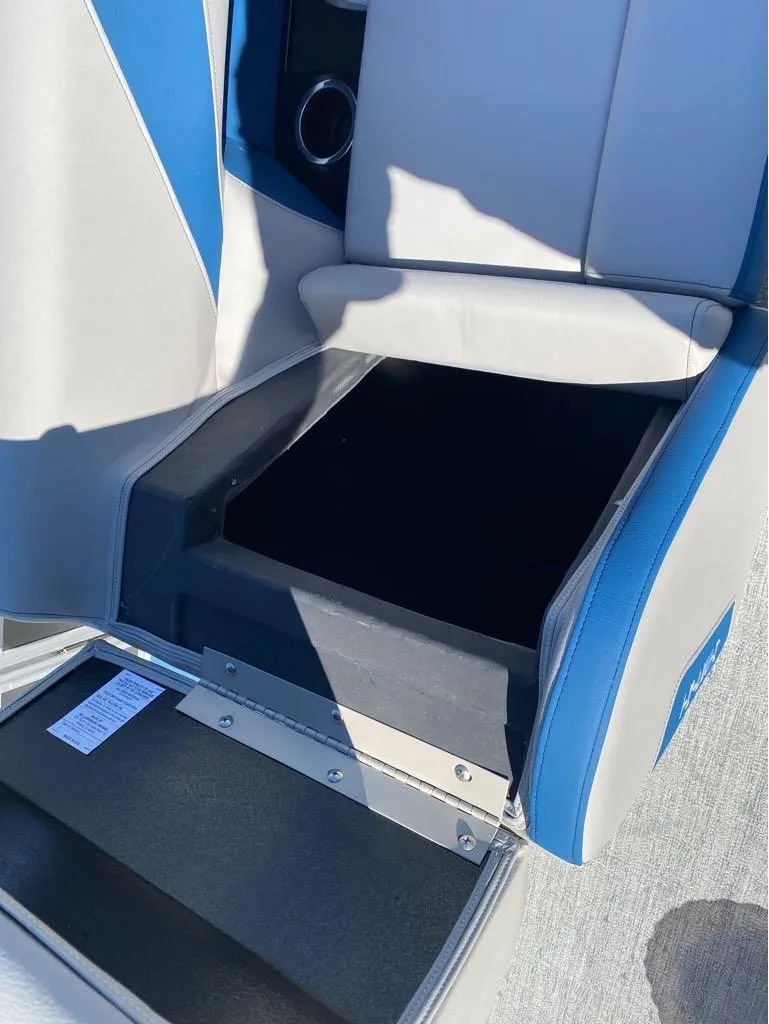 Slide: The Image of 2024 Trifecta 24 RF LE 2.75 boat seat storage compartment, open with blue and gray upholstery. - 9