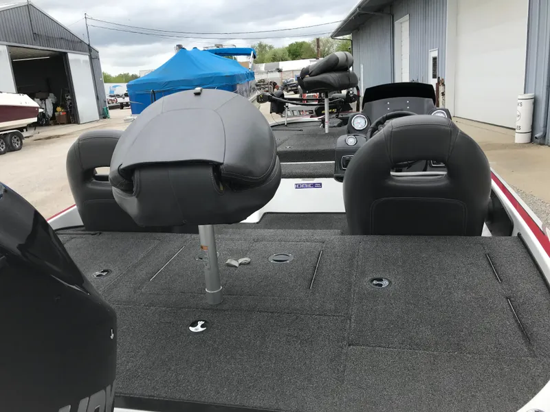 Slide: The Image of 2017 Nitro Z18 boat interior with seating and dashboard, parked near garages. - 17
