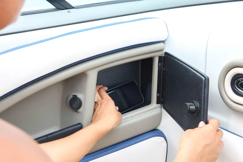 Slide: The Image of Person accessing storage compartment on 2025 Crownline 260 XSS boat interior. - 8