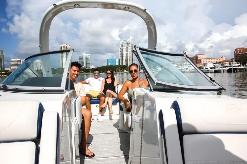 Slide: The Image of Four people relaxing on a 2025 Crownline 260 XSS boat in a city marina. - 6