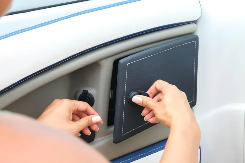 Slide: The Image of Hands adjusting a panel on a 2025 Crownline 260 XSS boat interior. - 8