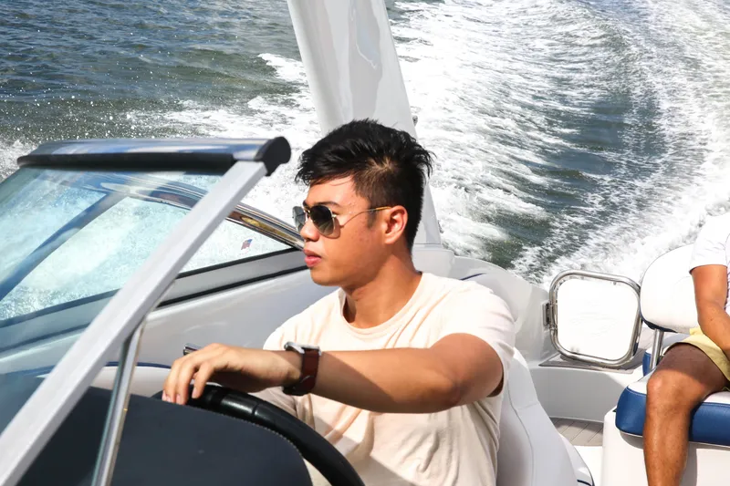 Slide: The Image of Man driving 2025 Crownline 260 XSS boat on water, wearing sunglasses. - 9