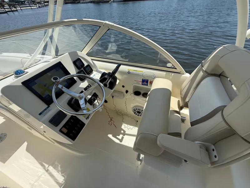 Slide: The Image of 2015 World Cat 255 DC boat cockpit with steering wheel and seating, overlooking water. - 15
