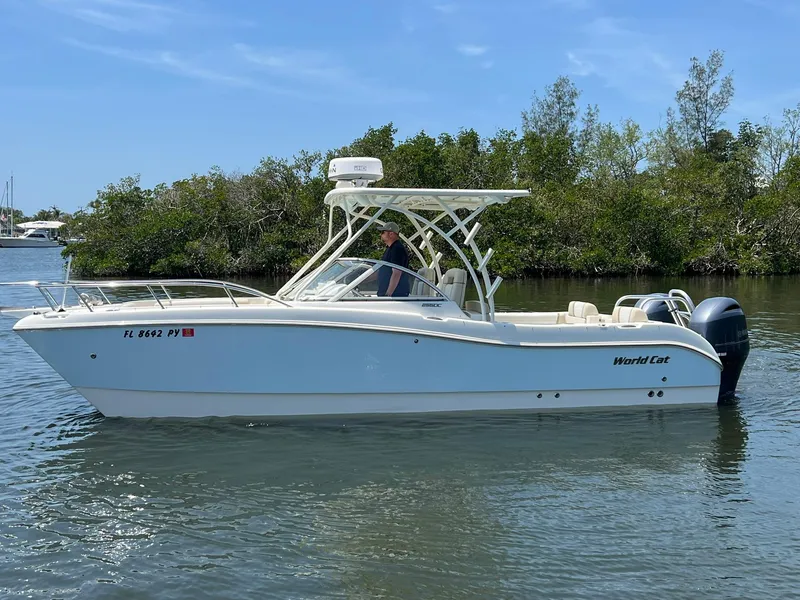 Slide: The Image of 2015 World Cat 255 DC boat on calm water, surrounded by lush greenery. - 4