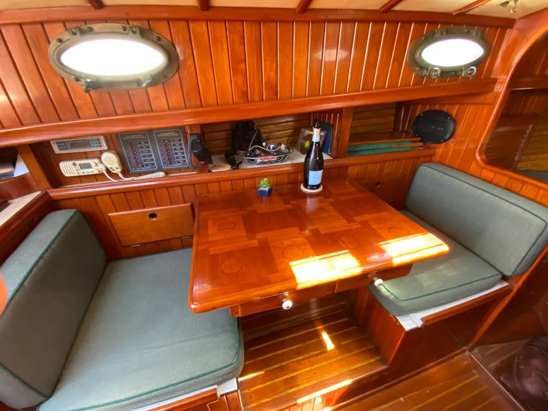 Slide: The Image of Cozy 1988 Custom Aft Cockpit boat interior with wooden dining area and seating. - 12