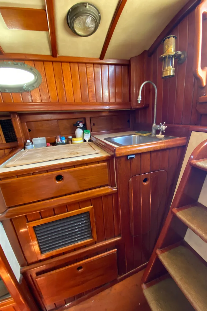 Slide: The Image of 1988 Custom Aft Cockpit interior with wooden cabinetry, sink, and stairs. - 14