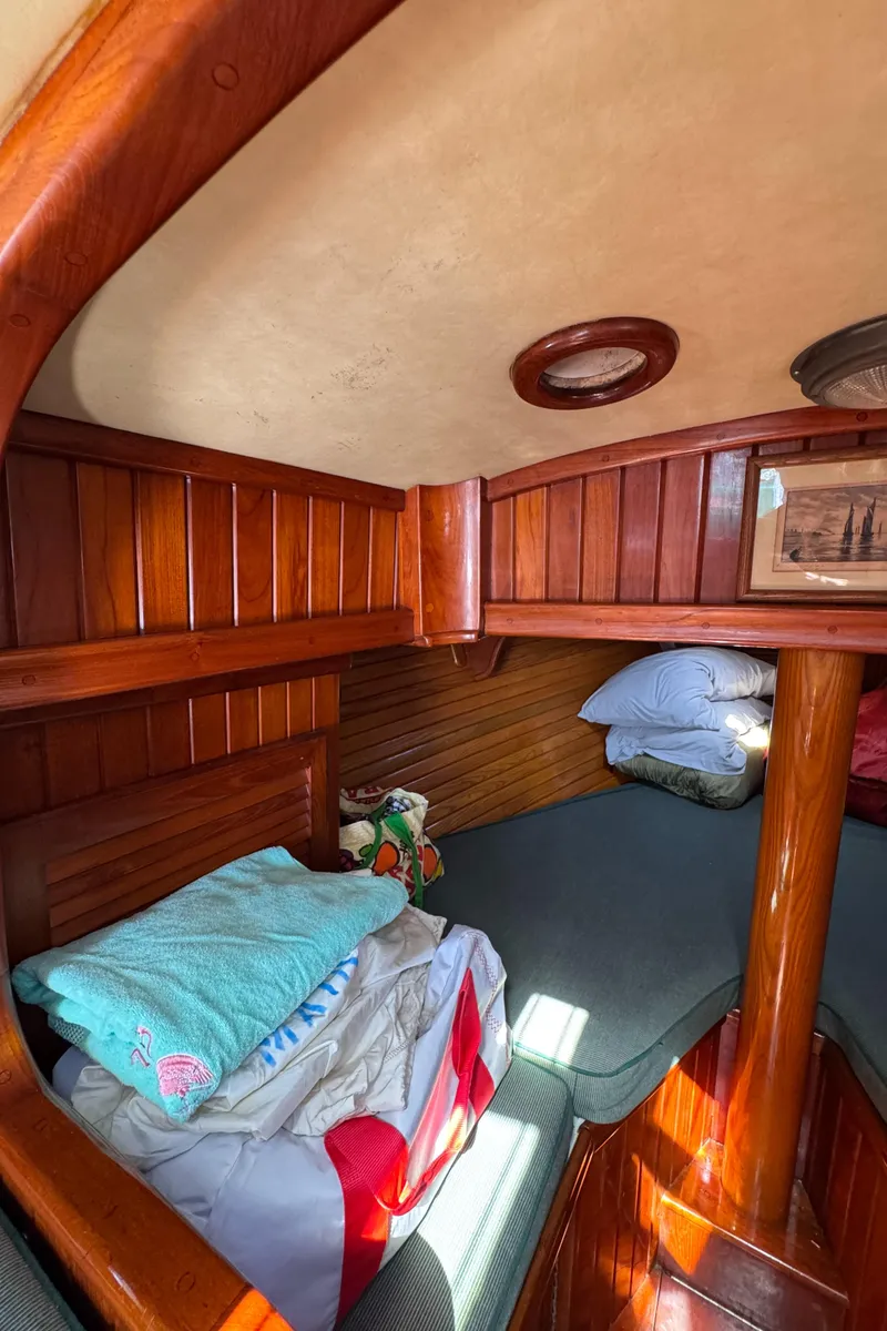 Slide: The Image of Cozy cabin interior of a 1988 Custom Aft Cockpit boat with wooden paneling and bedding. - 18