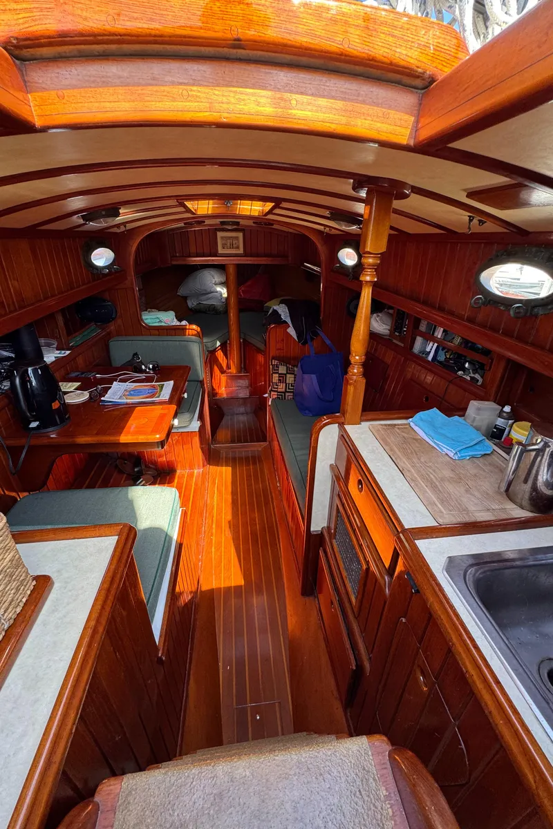 Slide: The Image of 1988 Custom Aft Cockpit interior with wooden finish, seating, and kitchenette. - 23