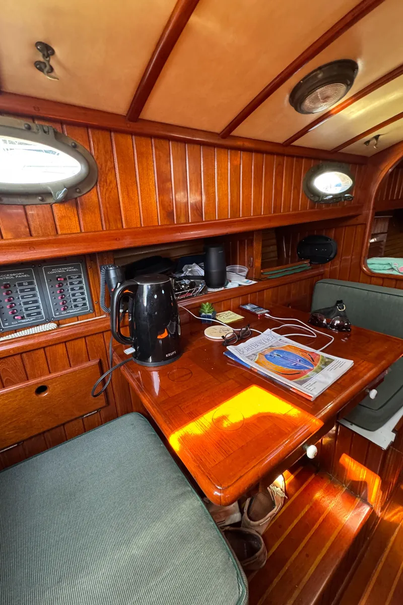 Slide: The Image of Cozy 1988 Custom Aft Cockpit interior with wooden paneling and a small dining area. - 25
