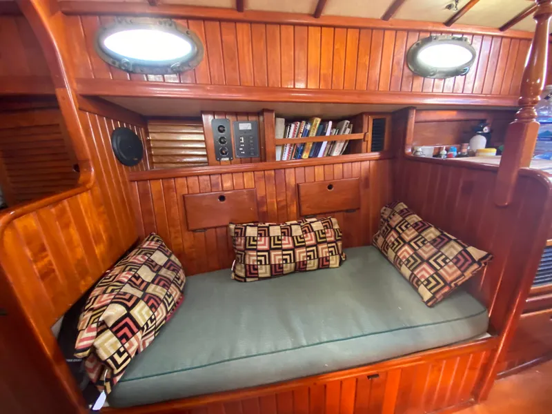 Slide: The Image of Cozy wooden boat cabin with cushioned seating, patterned pillows, and built-in bookshelf, 1988 Custom Aft Cockpit. - 9