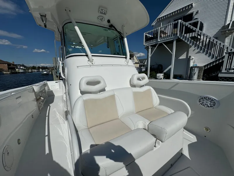 Slide: The Image of 2011 Everglades 325 Center Console boat with cushioned seating, docked near waterfront homes. - 17
