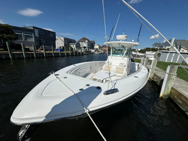 Slide: The Image of 2011 Everglades 325 Center Console boat docked in a marina under clear blue skies. - 2