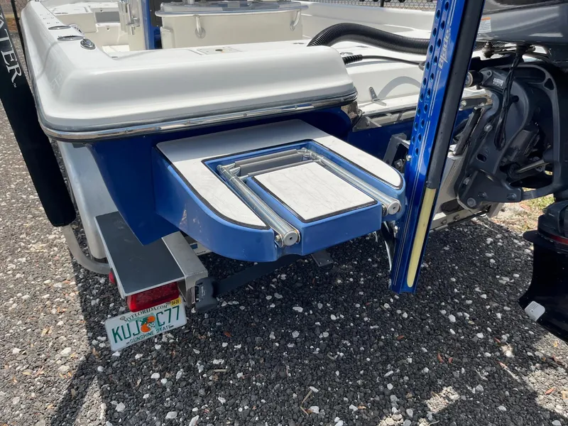 Slide: The Image of 2017 ShearWater 23LTZ boat with swim platform and motor, parked on gravel. - 1
