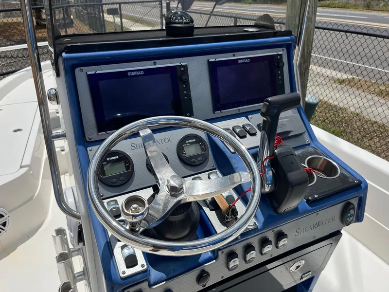 Slide: The Image of 2017 ShearWater 23LTZ boat dashboard with dual Simrad displays and steering wheel. - 10