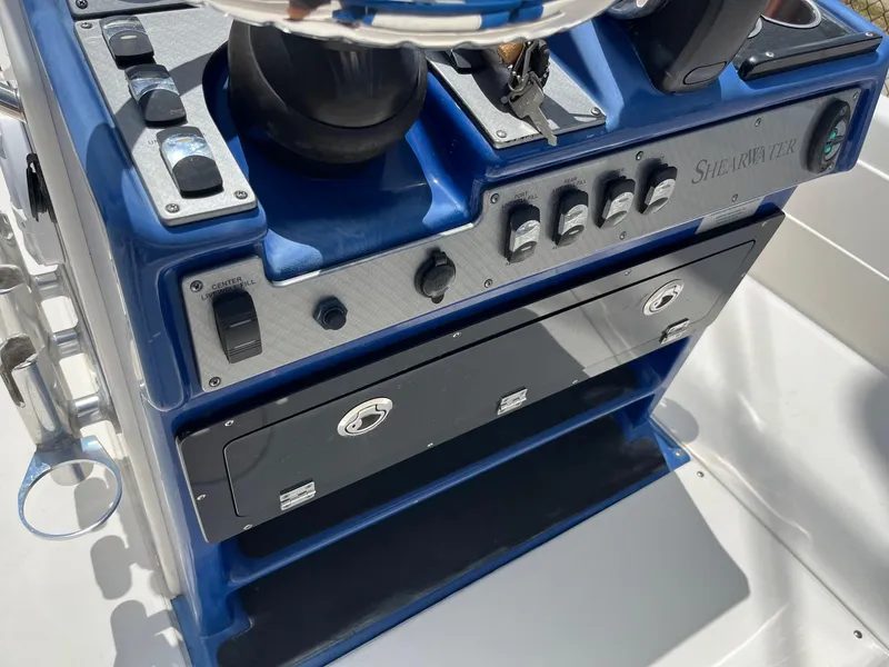 Slide: The Image of 2017 ShearWater 23LTZ boat console with blue and silver controls and storage compartments. - 11